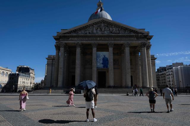 A tourist protects himself from the sun under an umbrella in front of the Pantheon in Paris on September 15, 2026. (Photo by Kenzo TRIBOUILLARD / AFP)