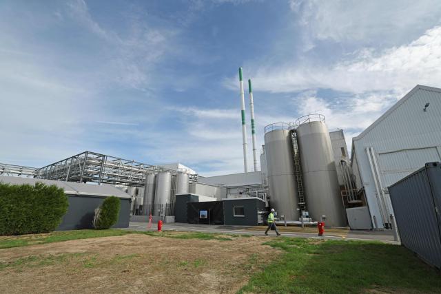This photograph taken in Steenvoorde on September 15, 2026, shows storage silos and chimneys at Danone's plant as a person walks by, during the inauguration of Danone's largest medical nutrition line in France. (Photo by Francois LO PRESTI / AFP)