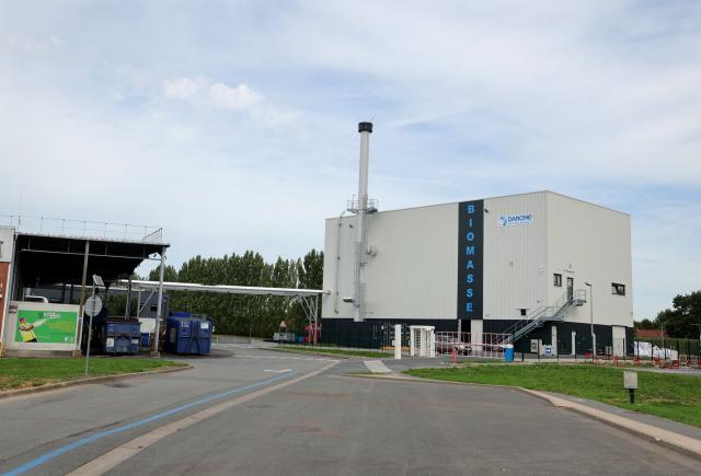 This photograph taken in Steenvoorde on September 15, 2026, shows the biomass boiler building at Danone's plant as a person walks past, during the inauguration of Danone's largest medical nutrition line in France. (Photo by Francois LO PRESTI / AFP)