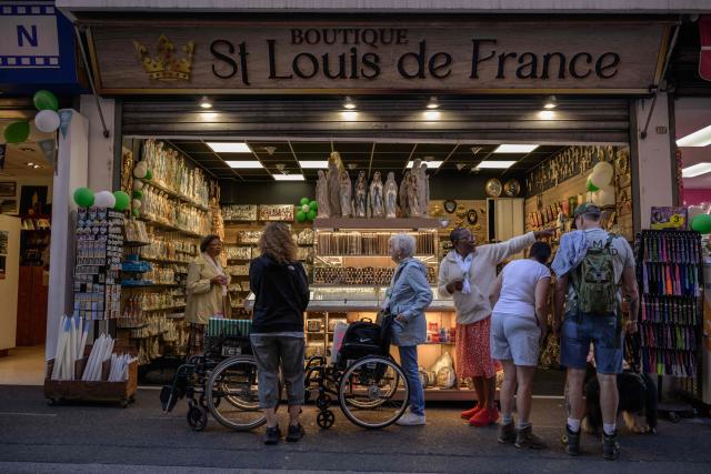 Clients browse through religious items displayed for sale at a shop in Lourdes on September 15, 2026. Pope Leo XIV will travel to Lourdes, a site of pilgrimage for Christians worldwide, where he will hold an open-air mass on Sunday, September 27, before presiding over another at the cathedral in the northeastern city of Metz on September 28. (Photo by Ed JONES / AFP)