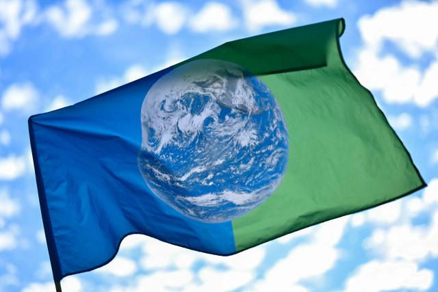 A flag displaying a photograph of Earth flutters during a demonstration "to say stop to climate austerity" called by a coalition of 53 organizations ahead of political discussions on an upcoming government budget and finance law near Bercy France's Ministry of the Economy in Paris on September 15, 2026. (Photo by LOU BENOIST / AFP)