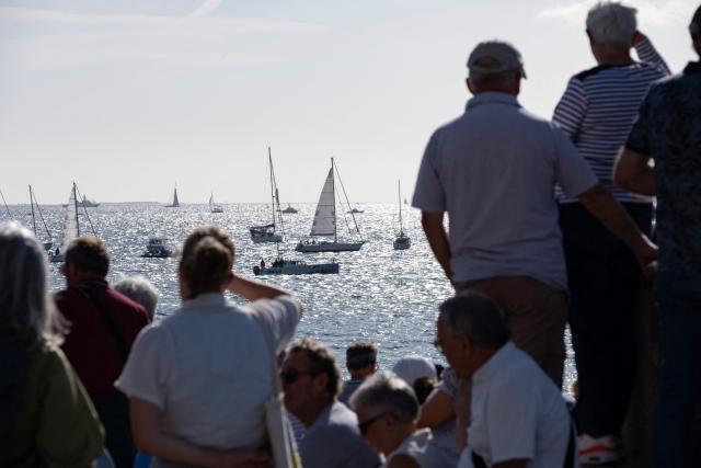 Attendees line the coast to watch sail boats navigate as part of a maritime tribute to the late sailor Charlie Dalin, in Concarneau, in Brittany, western France on September 15, 2026. French offshore sailor and Vendee Globe 2024/2025 winner Charlie Dalin has died in Quimper, western France, aged 42, from cancer, his family announced on June 11, 2026. (Photo by Oscar Chuberre / AFP)