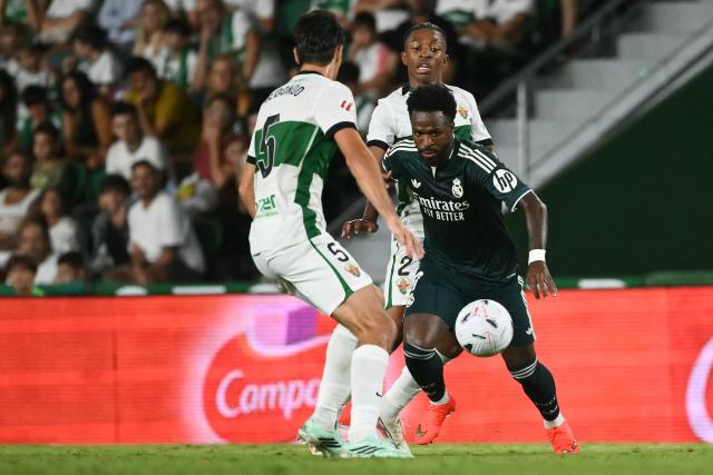Elche's Argentine midfielder #05 Federico Redondo Solari and Elche's Spanish defender #02 Buba Sangare fight for the ball with Real Madrid's Brazilian forward #07 Vinicius Junior during the Spanish league football match between Elche CF and Real Madrid CF at Martinez Valero Stadium in Elche on September 15, 2026. (Photo by JOSE JORDAN / AFP)