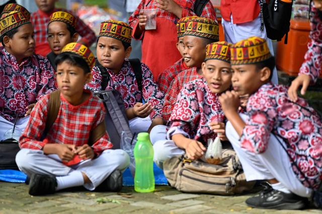 Students watch their schoolmates perform the rapa'i geleng, a traditional Acehnese dance, during a cultural schools exhibition in Banda Aceh on on September 16, 2026. (Photo by CHAIDEER MAHYUDDIN / AFP)