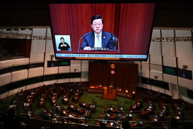 Hong Kong Chief Executive John Lee is seen on a television screen as he delivers Hong Kong's first five-year plan and his annual policy address at Central Government Offices chamber on September 16, 2026. (Photo by Peter PARKS / AFP)