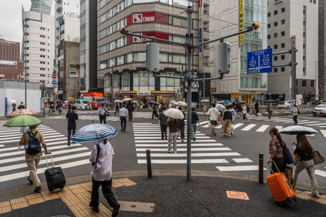 People use umbrellas to shelter themselves from the rain while crossing a road in Nagoya on September 16, 2026. (Photo by Mohd Rasfan / AFP)