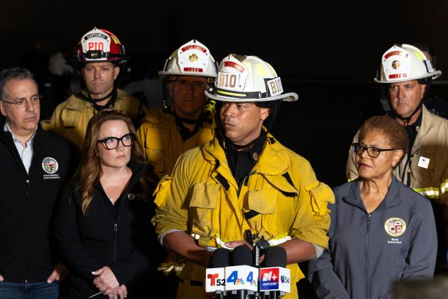 Los Angeles Fire Battalion Chief Rico Gross (C), accompanied by Los Angeles Mayor Karen Bass (R) briefs reporters after a US news media helicopter covering a deadly bus crash, came down in Chatsworth, a neighborhood of Los Angeles, California on September 15, 2026. Three people were killed and one person was hospitalized after the helicopter crashed between two commercial buildings,  igniting on fire instantly, according to the Los Angeles Fire Department. (Photo by Blake Fagan / AFP)