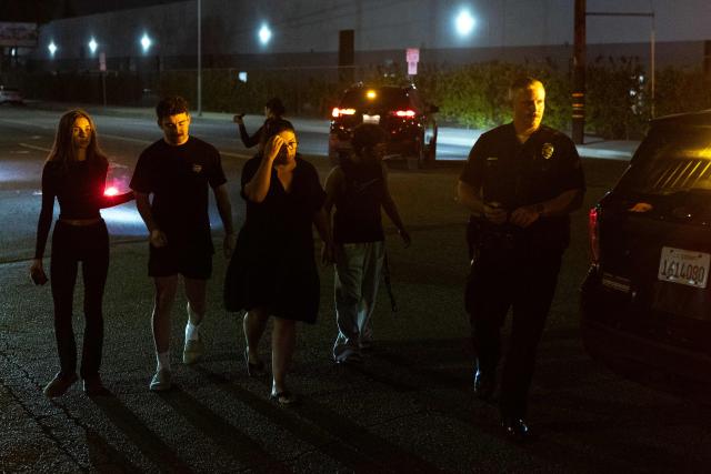 People are escorted by a Los Angeles Police officer near the scene where a US news media helicopter covering a deadly bus crash, came down in Chatsworth, a neighborhood of Los Angeles, California on September 15, 2026. Three people were killed and one person was hospitalized after the helicopter crashed between two commercial buildings,  igniting on fire instantly, according to the Los Angeles Fire Department. (Photo by Blake Fagan / AFP)