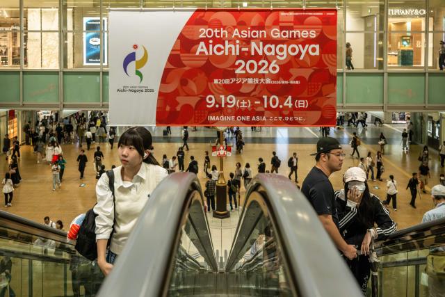 People ride escalators in front of a banner promoting the 2026 Asian Games at the train station in Nagoya, Aichi Prefecture on September 16, 2026. (Photo by Mohd Rasfan / AFP)