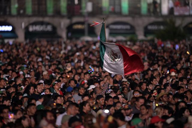 A person raises and waves a Mexico's flag above the crowd celebrating the traditional "Grito de Independencia" at the Zocalo square in Mexico City on September 15, 2026. (Photo by FRANYELI GARCIA / AFP)