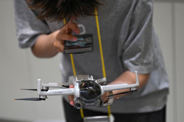 An employee at a drone reception module in a shopping mall inspects a drone brought in by its owner in Beijing on September 16, 2026. Authorities in Beijing have set up official points for residents to hand in their unmanned aircraft before November 15, when a total ban on possessing, storing and flying drones citywide takes effect. Owners can choose a government-subsidized buyback or recycling. (Photo by Pedro PARDO / AFP)