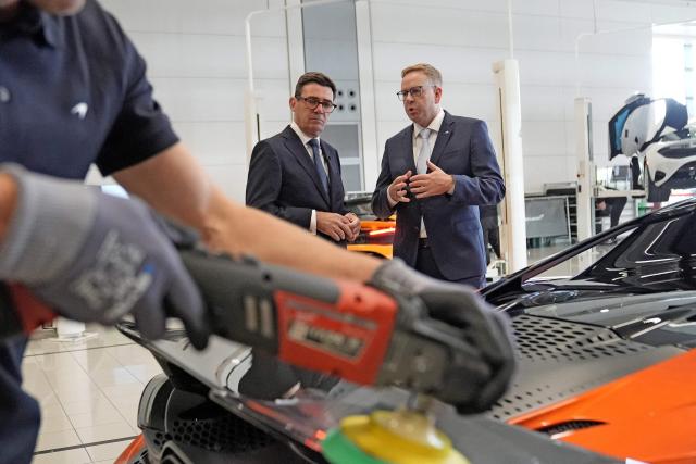 Nick Collins (R), chief executive officer of McLaren Group, speaks with Britain's Prime Minister Andy Burnham (C) during a visit to meet apprentices and workers on the production lines at the McLaren Technology Centre in Woking, Surrey, south-west of London on September 16, 2026. (Photo by Stefan Rousseau / POOL / AFP)