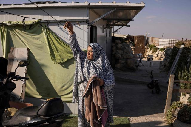 Arwa Amr looks on while taking clothes off a washing line outside the caves that her family has turned into their home in the village of Al-Tuwani, in the Israeli-occupied West Bank, on September 11, 2026. After his home was destroyed by Israeli forces in 2023, Mohammed Fadel Amr took shelter in caves, where he now lives with his two wives, Fatma Amr and Arwa Amr, and their eleven children. Mohammed and his family say they face almost daily harassment from settlers living in a nearby illegal Israeli settlement outpost. At the end of August 2026, Israeli forces reportedly ransacked the family's makeshift home during a night raid, and settlers later stole his goats, depriving him of his livelihood. (Photo by John WESSELS / AFP)