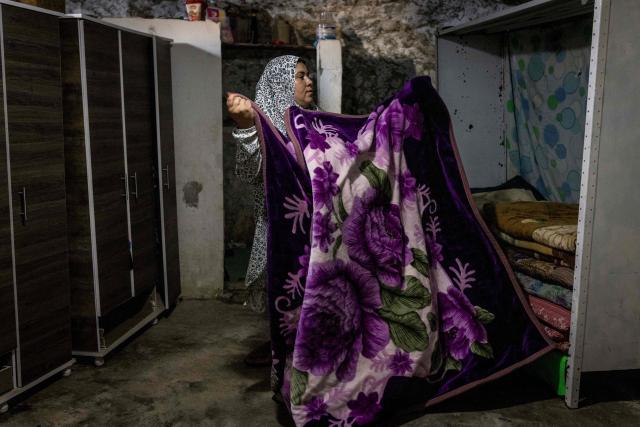 Arwa Amr folds a blanket as she repacks cupboards that were previously destroyed by Israeli forces inside the caves that her family has turned into their home in the village of Al-Tuwani, in the Israeli-occupied West Bank, on September 11, 2026. After his home was destroyed by Israeli forces in 2023, Mohammed Fadel Amr took shelter in caves, where he now lives with his two wives, Fatma Amr and Arwa Amr, and their eleven children. Mohammed and his family say they face almost daily harassment from settlers living in a nearby illegal Israeli settlement outpost. At the end of August 2026, Israeli forces reportedly ransacked the family's makeshift home during a night raid, and settlers later stole his goats, depriving him of his livelihood. (Photo by John WESSELS / AFP)