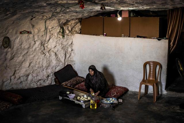 Fatma Amr bakes cakes at the cave that her family has turned into their home in the village of Al-Tuwani, in the Israeli-occupied West Bank, on September 11, 2026. After his home was destroyed by Israeli forces in 2023, Mohammed Fadel Amr took shelter in caves, where he now lives with his two wives, Fatma Amr and Arwa Amr, and their eleven children. Mohammed and his family say they face almost daily harassment from settlers living in a nearby illegal Israeli settlement outpost. At the end of August 2026, Israeli forces reportedly ransacked the family's makeshift home during a night raid, and settlers later stole his goats, depriving him of his livelihood. (Photo by John WESSELS / AFP)