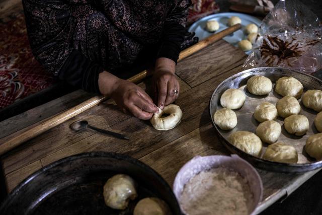 Fatma Amr bakes cakes at the cave that her family has turned into their home in the village of Al-Tuwani, in the Israeli-occupied West Bank, on September 11, 2026. After his home was destroyed by Israeli forces in 2023, Mohammed Fadel Amr took shelter in caves, where he now lives with his two wives, Fatma Amr and Arwa Amr, and their eleven children. Mohammed and his family say they face almost daily harassment from settlers living in a nearby illegal Israeli settlement outpost. At the end of August 2026, Israeli forces reportedly ransacked the family's makeshift home during a night raid, and settlers later stole his goats, depriving him of his livelihood. (Photo by John WESSELS / AFP)