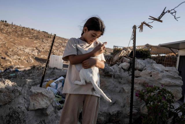Palestinian girl Hadeel hugs her cat, Lulu, outside the cave that her family has turned into their home in the village of Al-Tuwani, in the Israeli-occupied West Bank, on September 11, 2026. After his home was destroyed by Israeli forces in 2023, Mohammed Fadel Amr took shelter in caves, where he now lives with his two wives, Fatma Amr and Arwa Amr, and their eleven children. Mohammed and his family say they face almost daily harassment from settlers living in a nearby illegal Israeli settlement outpost. At the end of August 2026, Israeli forces reportedly ransacked the family's makeshift home during a night raid, and settlers later stole his goats, depriving him of his livelihood. (Photo by John WESSELS / AFP)