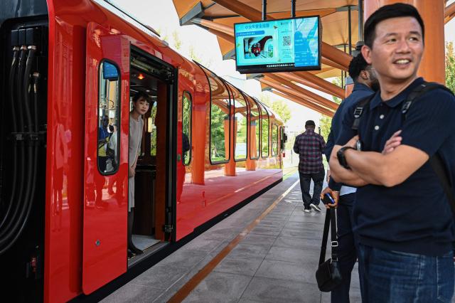 An attendant (L) looks out from a shuttle train at Huawei Lianqiu Lake research campus during a media tour in Shanghai on on September 16, 2026. (Photo by Jade GAO / AFP)
