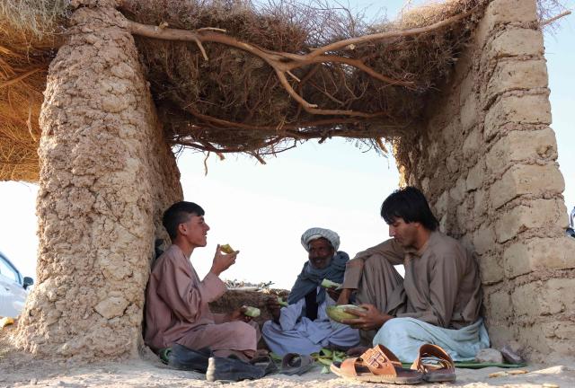 Afghan men eat melon under a canopy along a street in the Adraskan district of Afghanistan's Herat province on September 16, 2026. (Photo by Mohsen KARIMI / AFP)