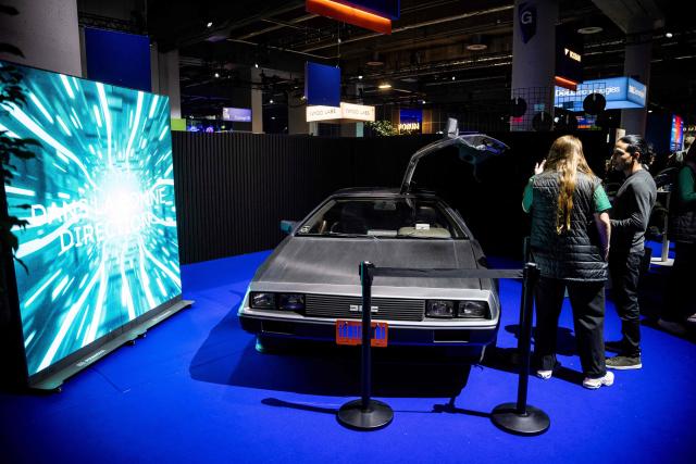 People look at a DMC DeLorean in front of a booth on day one of the Al In 2026 conference at the Palais des Congres de Montreal in Montreal, Quebec, on September 16, 2026. All In is Canada's largest artificial intelligence and technology event. (Photo by ANDREJ IVANOV / AFP)