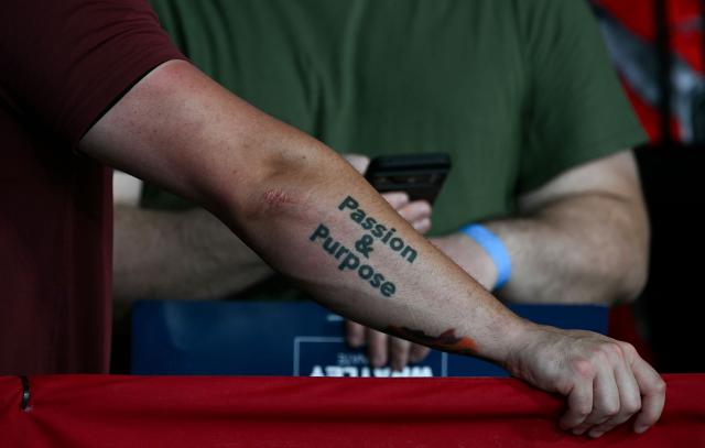A supporter wears a "Passion & Purpose" tattoo on their forearm as they listen to US President Donald Trump speak at a rally at Gastonia Municipal Airport in Gastonia, North Carolina, on September 16, 2026. Trump is campaigning for Republican US Senate candidate Michael Whatley. (Photo by Brendan SMIALOWSKI / AFP)