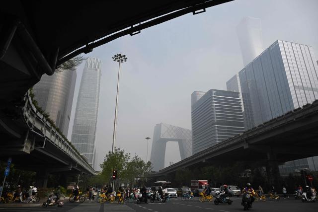 People ride on a road on a polluted day in the central business district of Beijing on September 17, 2026. (Photo by GREG BAKER / AFP)
