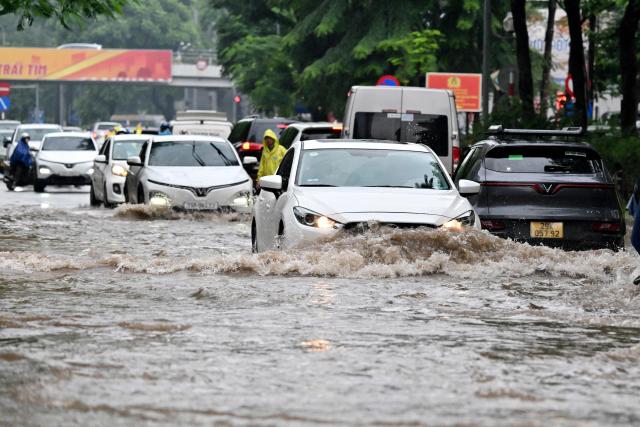 Cars drive along a flooded street in Hanoi on September 17, 2026. (Photo by Nhac NGUYEN / AFP)