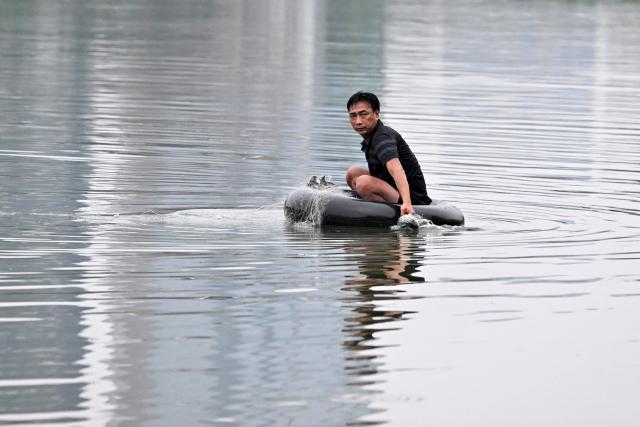 TOPSHOT - A man sits on a car inner tube to fish in a lake in Hanoi on September 17, 2026. (Photo by Nhac NGUYEN / AFP)