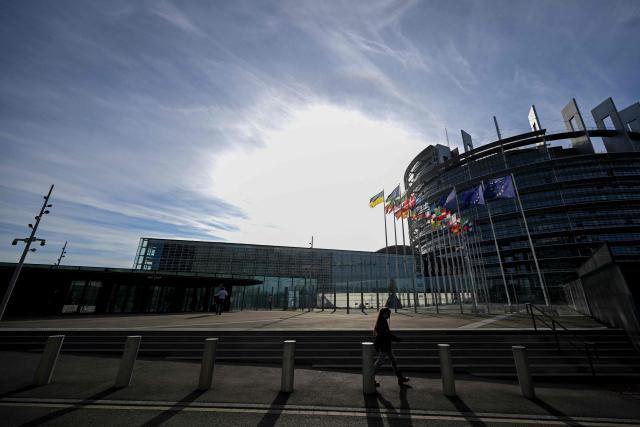 Pedestrians walk past the European flag surrounded by the national flags of the EU member states flapping in the breeze in front of the Louise Weiss building, headquarters of the European Parliament, in Strasbourg, eastern France on September 17, 2026. (Photo by Jean-Christophe VERHAEGEN / AFP)
