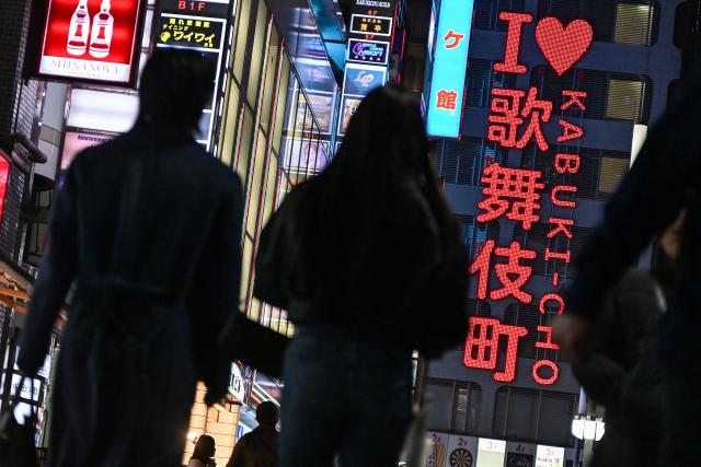 (FILES) This photo taken on March 31, 2025 shows people walking down a street by the "I love Kabukicho" neon sign in the red-light entertainment area of Kabukicho in the Shinjuku district of Tokyo. Japan should overhaul its prostitution law to punish those who seek to buy sex, experts recommended on September 17, 2026 in proposals likely to lead to changes to the decades-old legislation. (Photo by Richard A. Brooks / AFP)