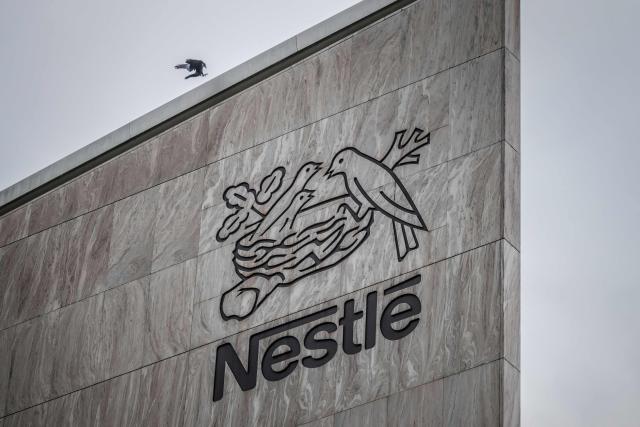 (FILES) This photograph shows a bird of the crow family flying next to the logo of Swiss food giant Nestle on the facade of its headquarters ahead of the companys third-quarter results announcement, in Vevey, western Switzerland, on October 14, 2025. Nestlé, sued over illegal dumping near its bottled water plants in the Vosges, western France must be retried, the Nancy Court of Appeal ruled on September 17, 2026, overturning a decision by the criminal court that had annulled in March key analyses implicating the multinational. (Photo by Fabrice COFFRINI / AFP)