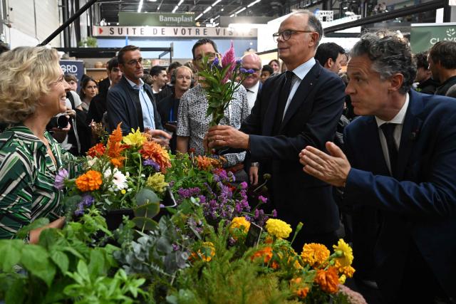 Right wing party Horizons candidate in France's 2027 presidential election Edouard Philippe (C), flanked by Mayor of Angers Christophe Bechu (R), looks at a plant as he visits the 'Salon du Vegetal' (plant fair) in Angers, western France on September 17, 2026. (Photo by Sebastien Salom-Gomis / AFP)