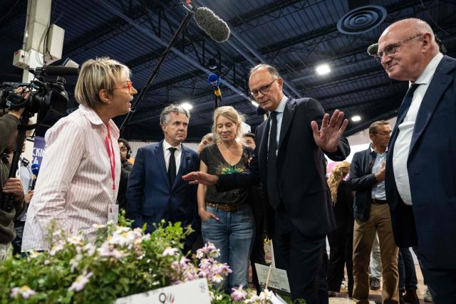 Right wing party Horizons candidate in France's 2027 presidential election Edouard Philippe (C-R), flanked by Mayor of Angers Christophe Bechu (C-L), gestures as he visits the 'Salon du Vegetal' (plant fair) in Angers, western France on September 17, 2026. (Photo by Sebastien Salom-Gomis / AFP)