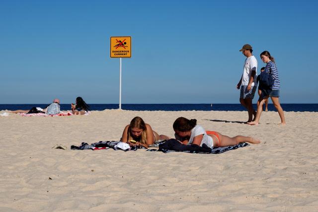 People spend their afternoon on a sunny day on Bondi Beach in Sydney on September 18, 2026. Australia will detain tourists who overstay visas to send a message of deterrence under new rules aimed at reducing levels of migration, a minister said on September 18. (Photo by Xiaoyu Yin / AFP)