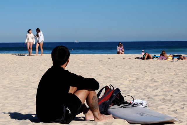 People spend their afternoon on a sunny day on Bondi Beach in Sydney on September 18, 2026. Australia will detain tourists who overstay visas to send a message of deterrence under new rules aimed at reducing levels of migration, a minister said on September 18. (Photo by Xiaoyu Yin / AFP)