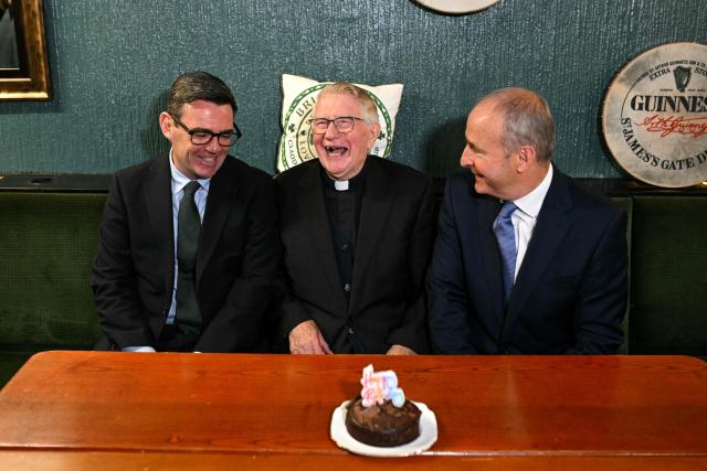 Britain's Prime Minister Andy Burnham (L) and Ireland's Prime Minister Micheal Martin (R) smile beside Canon Patrick J MacNally on his 90th birthday during a visit to the Brian Boru Irish Club in, Ashton-in-Makerfield, northern England, on September 18, 2026. (Photo by Oli SCARFF / POOL / AFP)