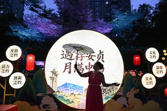 A woman poses for photographs as she visits a lantern festival to mark the beginning of the autumn season in Beijing on September 18, 2026. (Photo by ADEK BERRY / AFP)