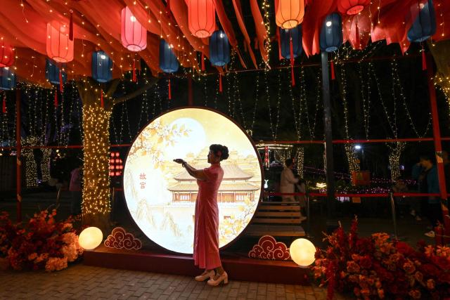 A woman poses for photographs as she visits a lantern festival to mark the beginning of the autumn season in Beijing on September 18, 2026. (Photo by ADEK BERRY / AFP)