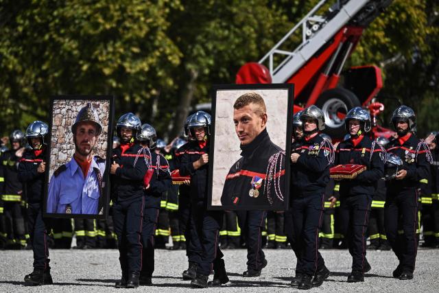 Colleagues carry portraits of late fire-fighters Anthony Berthome (R) and Wilfried Schmitter (L), who died on July 21, 2026 whilst fighting a fire in Merignac, during an official memorial ceremony in Bordeaux, south-western France on September 18, 2026. A national tribute, presided over by the Minister of the Interior, was paid in Bordeaux to the two professional firefighters who died in July while battling a blaze in Merignac, near the Gironde airport. Minister of the Interior Laurent Nunez posthumously awarded the Legion of Honour to Corporals Anthony Berthome and Wilfried Schmitter, whose truck had become trapped in a pine grove engulfed in flames.He also presented them with the Medal of Internal Security. (Photo by Christophe ARCHAMBAULT / AFP)