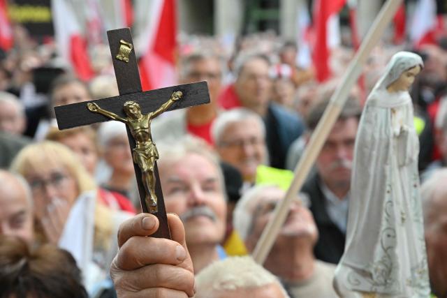 An anti-government protestor holds a crucifix and a Virgin Mary figurine during a rally outside the Constitutional Court building in Warsaw on September 18, 2026. Over one thousand demonstrators rallied in Warsaw on September 18 to protest the ruling centrist governments moves to investigate the barring of several elected judges from adjudicating in Poland's highest court. (Photo by Mladen ANTONOV / AFP)