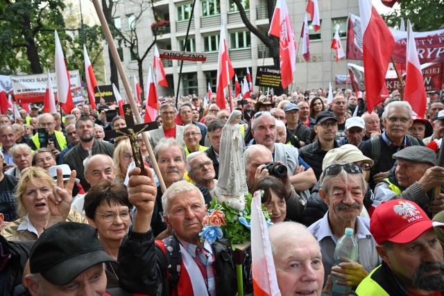 An anti-government protestor holds a crucifix and a Virgin Mary figurine during a rally outside the Constitutional Court building in Warsaw on September 18, 2026. Over one thousand demonstrators rallied in Warsaw on September 18 to protest the ruling centrist governments moves to investigate the barring of several elected judges from adjudicating in Poland's highest court. (Photo by Mladen ANTONOV / AFP)