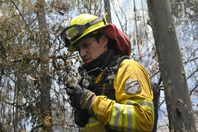 A firefighter works to control a fire on the southern side of Casitagua Hill, in northern Quito on September 18, 2026. Firefighters battled wildfires sweeping through a forest in Ecuador's capital Quito on September 18, with authorities saying they had evacuated dozens of people. (Photo by Rodrigo BUENDIA / AFP)