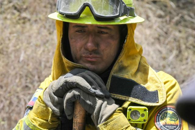 A firefighter works to control a fire on the southern side of Casitagua Hill, in northern Quito on September 18, 2026. Firefighters battled wildfires sweeping through a forest in Ecuador's capital Quito on September 18, with authorities saying they had evacuated dozens of people. (Photo by Rodrigo BUENDIA / AFP)