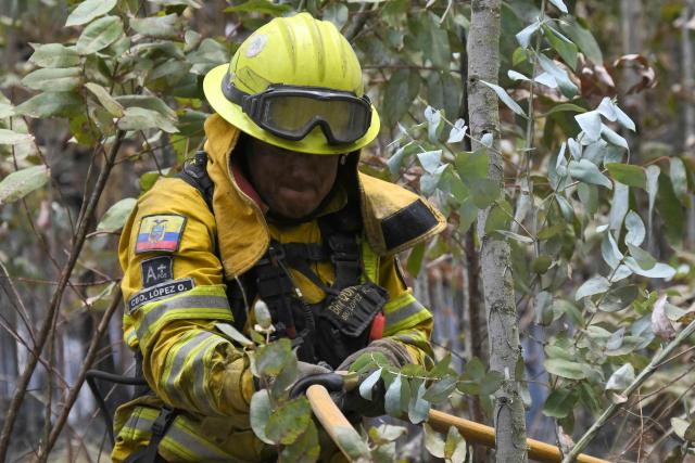 A firefighter works to control a fire on the southern side of Casitagua Hill, in northern Quito on September 18, 2026. Firefighters battled wildfires sweeping through a forest in Ecuador's capital Quito on September 18, with authorities saying they had evacuated dozens of people. (Photo by Rodrigo BUENDIA / AFP)