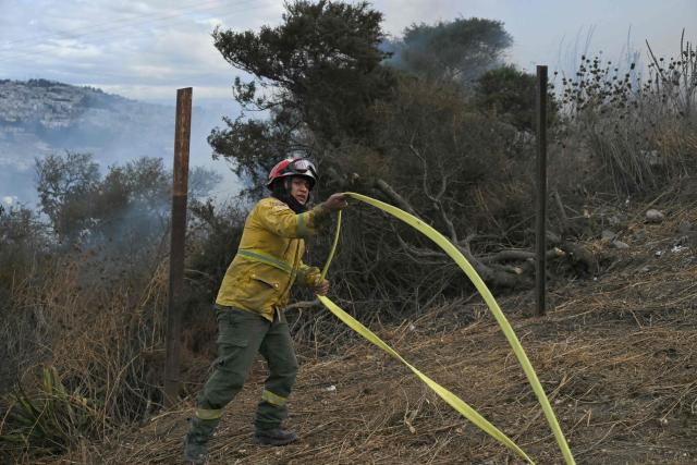 A firefighter works to control a fire on the southern side of Casitagua Hill, in northern Quito on September 18, 2026. Firefighters battled wildfires sweeping through a forest in Ecuador's capital Quito on September 18, with authorities saying they had evacuated dozens of people. (Photo by Rodrigo BUENDIA / AFP)