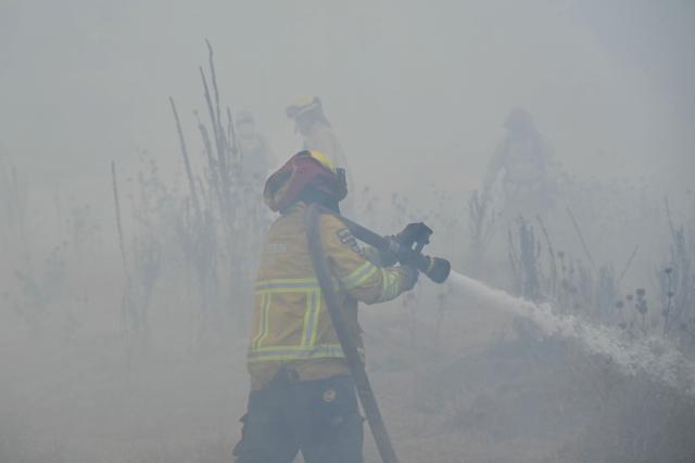 A firefighter works to control a fire on the southern side of Casitagua Hill, in northern Quito on September 18, 2026. Firefighters battled wildfires sweeping through a forest in Ecuador's capital Quito on September 18, with authorities saying they had evacuated dozens of people. (Photo by Rodrigo BUENDIA / AFP)
