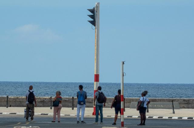 People wait for public transport at an intersection with traffic lights out during a blackout in Havana on September 18, 2026. Cuba was plunged into its seventh massive blackout of the year on September 18, 2026, the energy ministry said, as fuel shortages bite on the US-blockaded island. (Photo by ADALBERTO ROQUE / AFP)