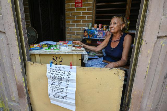 An elderly woman sells goods from her doorway during a blackout in Havana on September 18, 2026. Cuba was plunged into its seventh massive blackout of the year on September 18, 2026, the energy ministry said, as fuel shortages bite on the US-blockaded island. (Photo by ADALBERTO ROQUE / AFP)