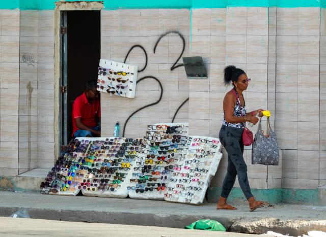 A woman walks past glasses for sale during a blackout in Havana on September 18, 2026. Cuba was plunged into its seventh massive blackout of the year on September 18, 2026, the energy ministry said, as fuel shortages bite on the US-blockaded island. (Photo by ADALBERTO ROQUE / AFP)
