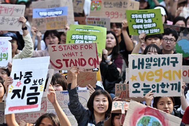 Environmental activists hold placards during a Climate Justice March in Seoul on September 19, 2026. (Photo by Lillian SUWANRUMPHA / AFP)